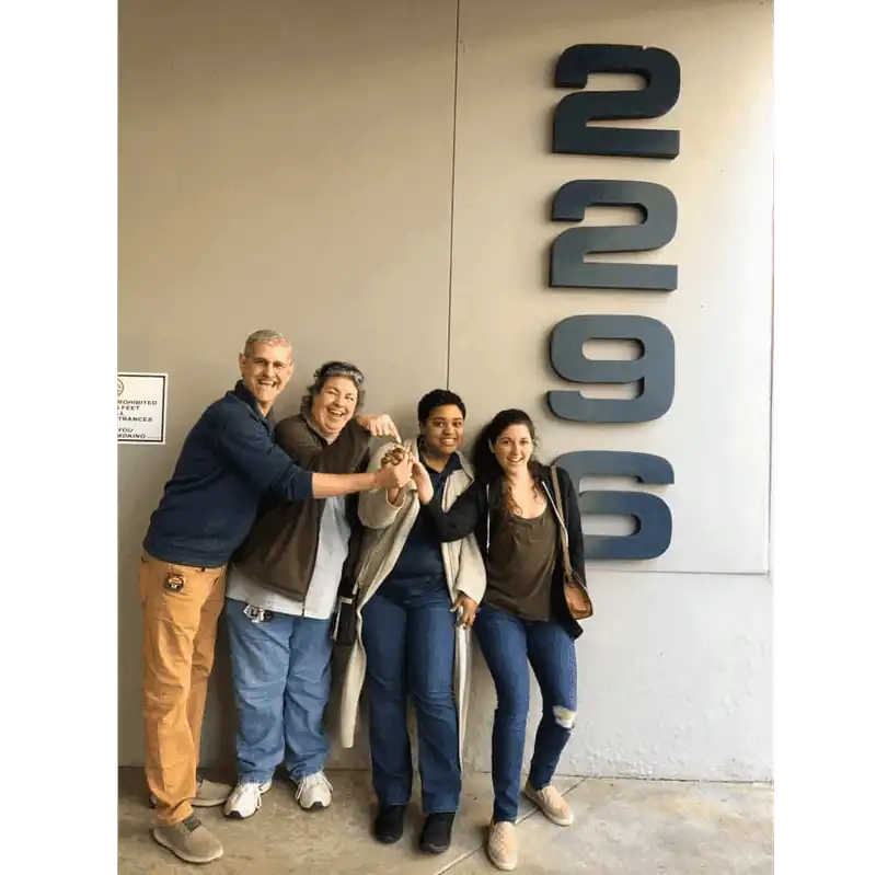 GCDHH staff members stand excitedly outside their new office building, which large numbers 2296 are visible on the right.