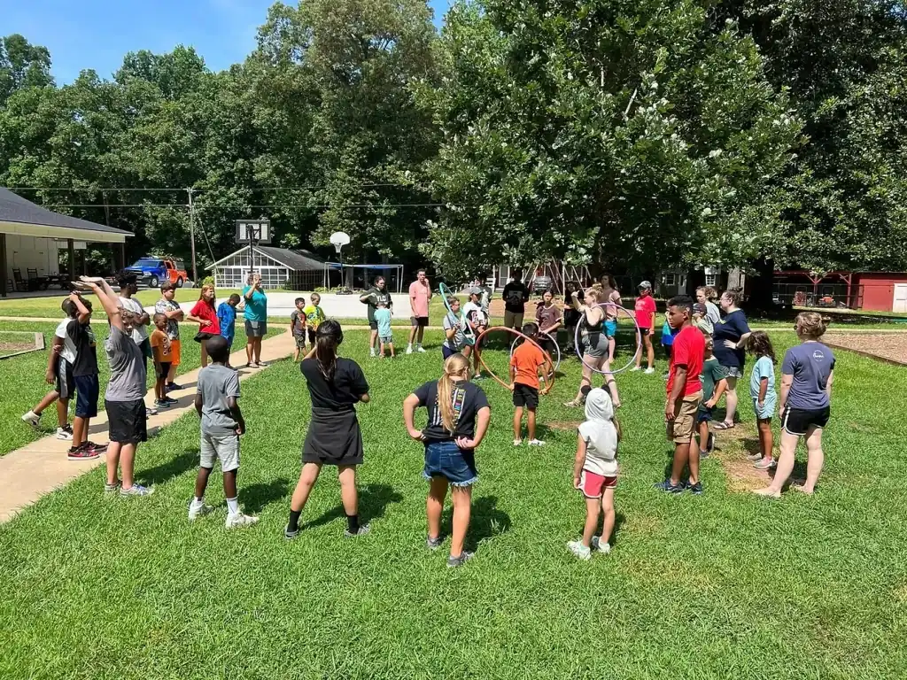 Large group of campers and staff participating in an outdoor activity on a grassy field.