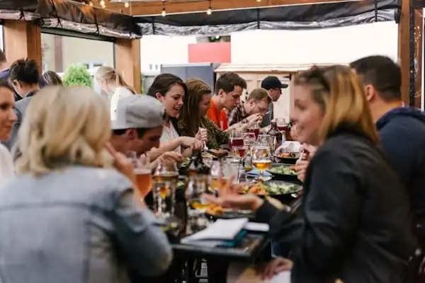 A large group of people enjoying a meal together at a long table outdoors.