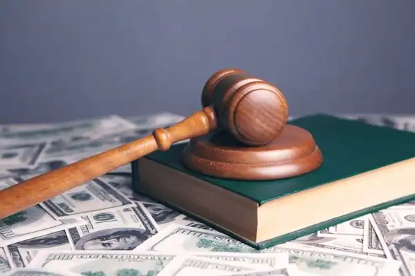 Gavel on a green book, sitting on a pile of money.